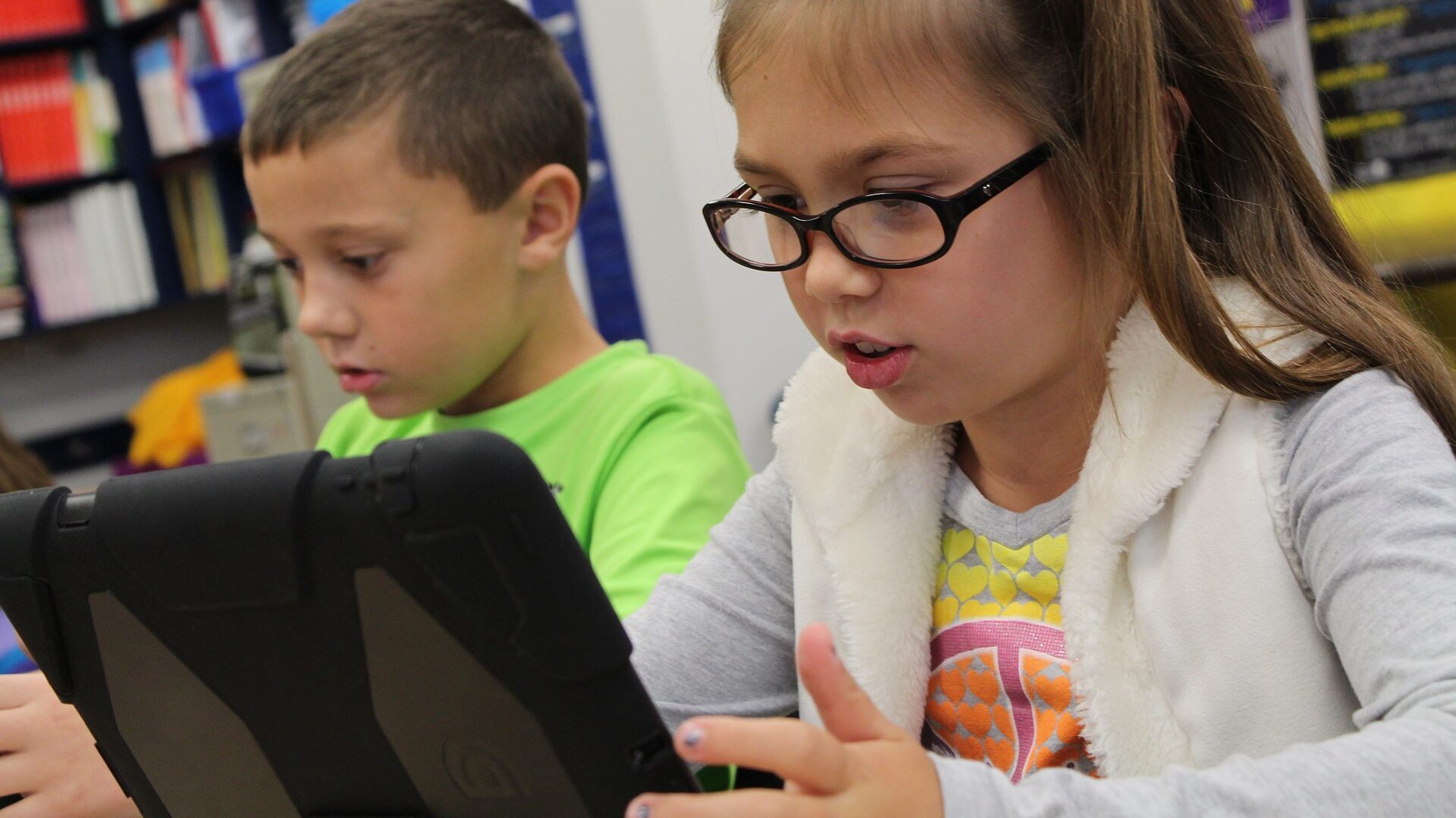 Ein Mädchen und ein Junge in der Schule arbeiten an einem Tablet